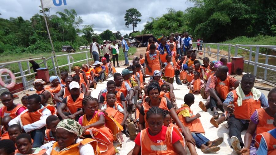 Ivorian returnees wear lifejackets for the crossing of the Cavalla River on a UNHCR-chartered barge.