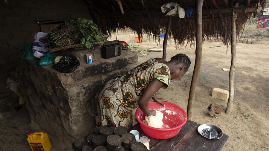 Rose kneads dough in front of an oven at the home of Sister Angélique Namaika in Dungu