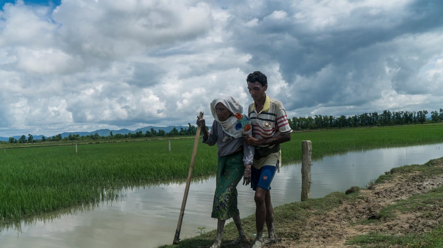 Bangladesh. An elderly Rohingya refugee is helped cross the border