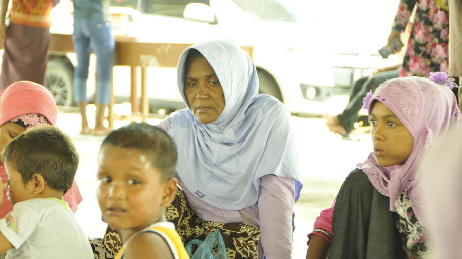 A small group of women and children sit on the floor.