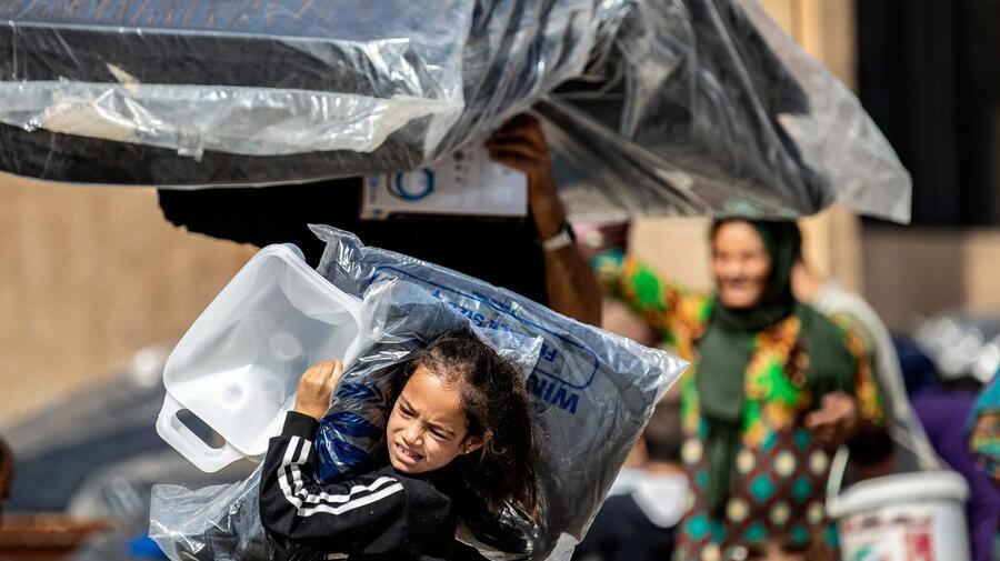 Syria. Young girl displaced by recent violence carries relief supplies