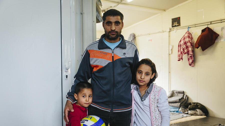 An Afghan asylum-seeker stands with two of his children at a reception centre in Fylakio, Greece, in February 2020.