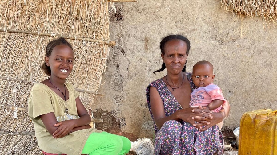 Sudan. An Ethiopian refugee mother sits outside her shelter in Village 8 with her young children.