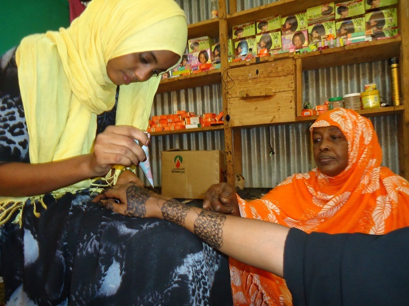 Fatuma applies henna to one of her customers in Ifo camp.