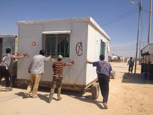 Photo of Syrian ‘removal men’ transporting a shelter inside Za’atari camp. Photo by Nina Weaver.