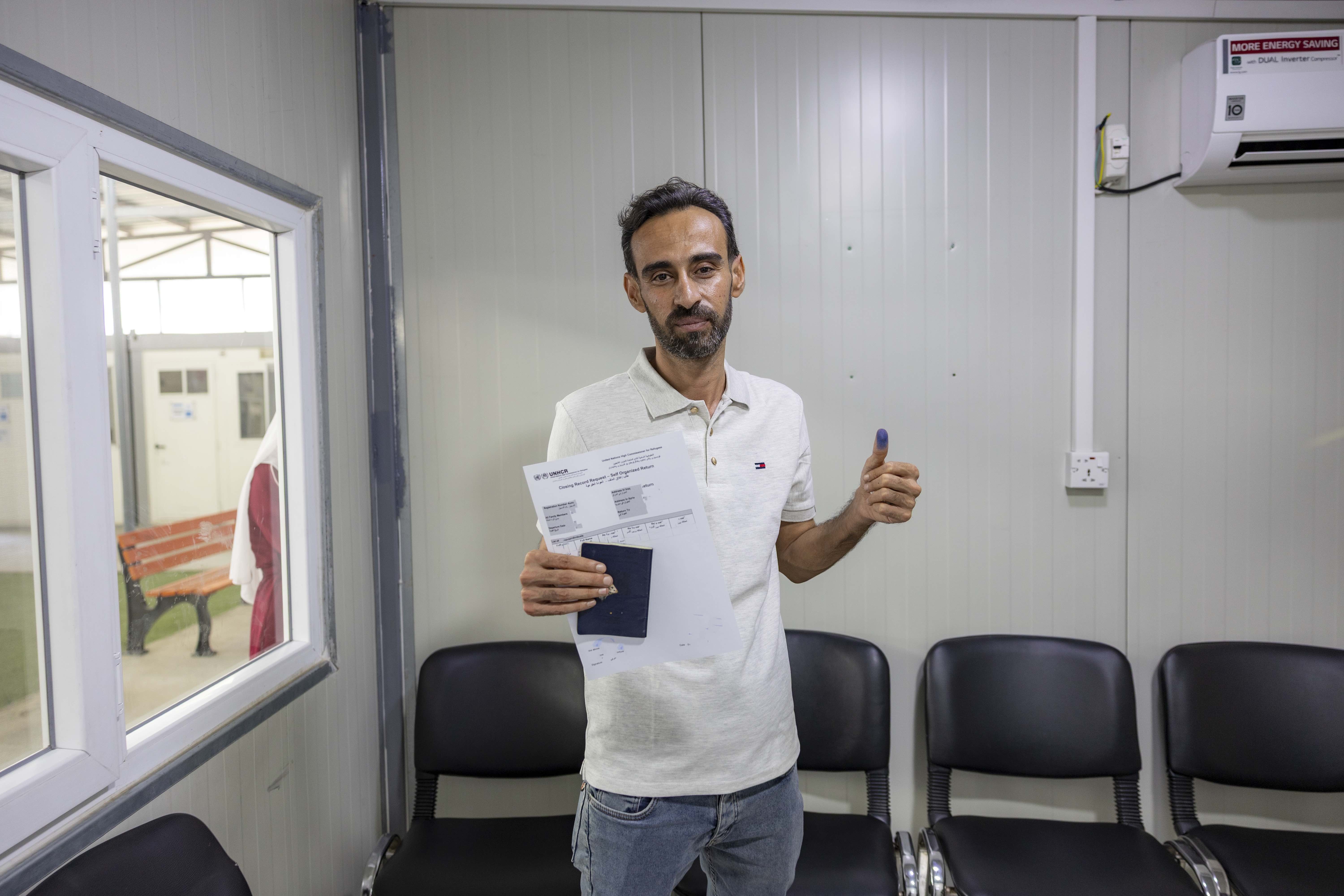 Hussein flashes an ‘okay’ sign after completing his return application to Syria.