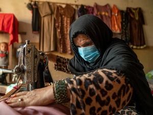 An internally displaced woman living in Jalalabad city in Nangarhar Province works on a garment she is sewing for a customer