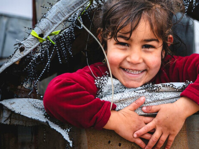 Girl smiling in a tent in refugee camp in Jordan