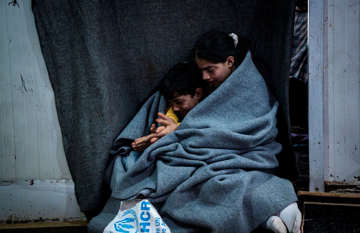 Bambina di 11 anni abbraccia il fratellino di 6 sotto una coperta UNHCR nel campo profughi di Zaatari, Giordania.
