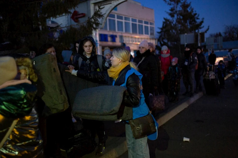 Il personale dell'UNHCR distribuisce coperte termiche al valico di frontiera di Shehyni alle persone costrette a fuggire dall'Ucraina in attesa di entrare in Polonia. © UNHCR/Valerio Muscella