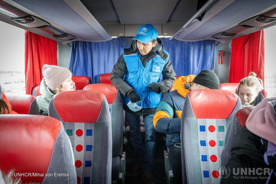 Il responsabile della protezione dell'UNHCR Batyr Sapbyiev parla con i rifugiati ucraini durante un trasferimento in autobus dalla Moldavia alla Romania. © UNHCR/Mihai Eremia