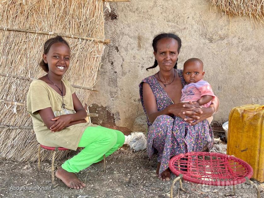 Sudan. An Ethiopian refugee mother sits outside her shelter in Village 8 with her young children.