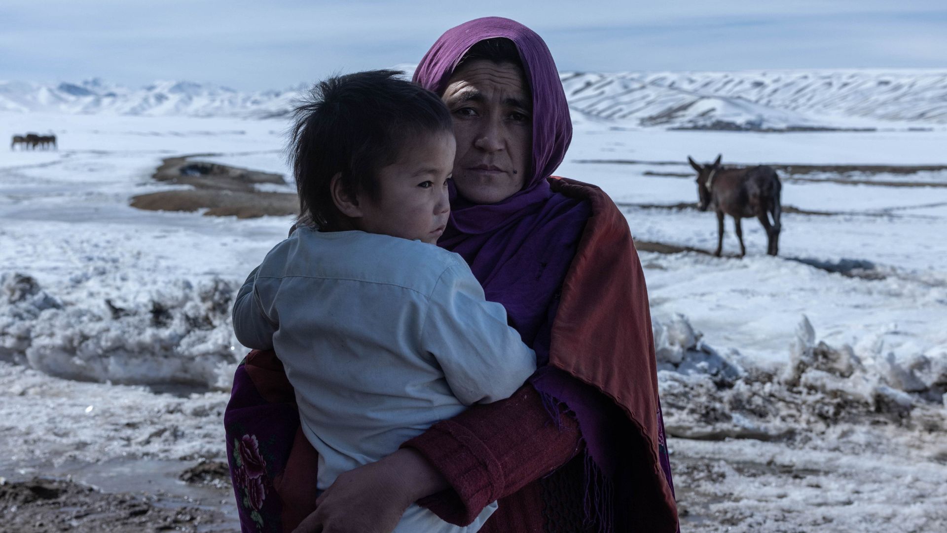 Donna afghana con bambino nel gelo invernale
