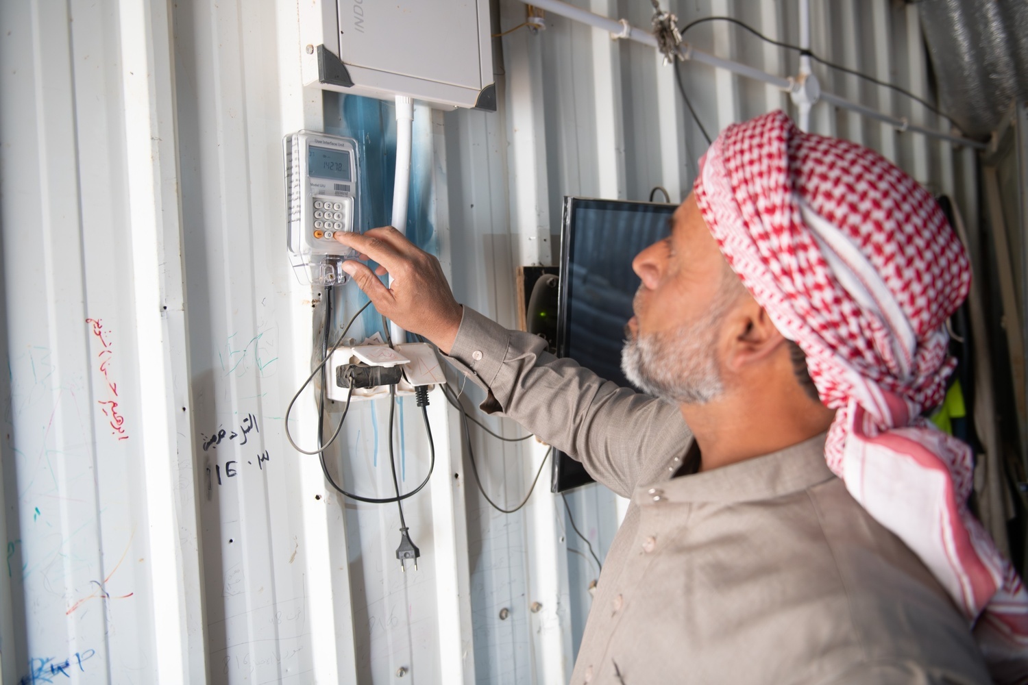 Abu Zainab monitors his electricity consumption from the comfort of his home using the display screen installed by UNHCR.