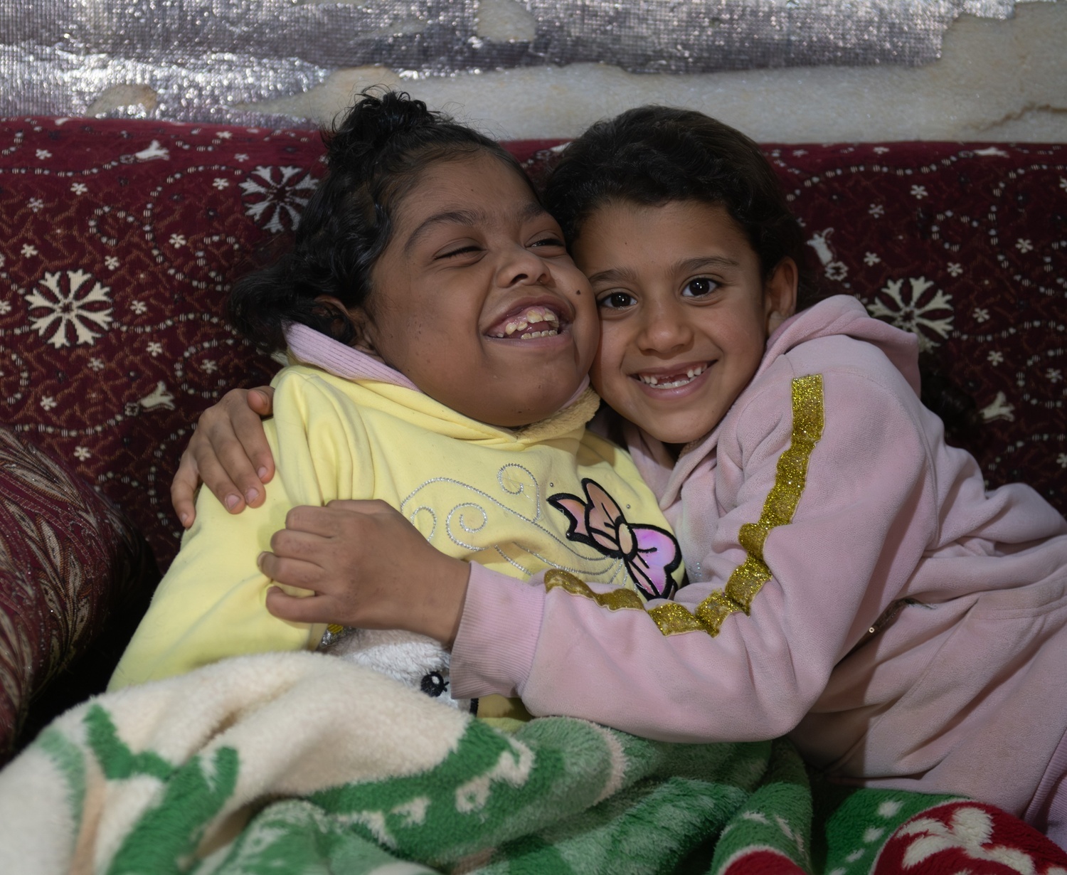 Zeinab, hugging her sister Mariam while watching her favorite cartoon show