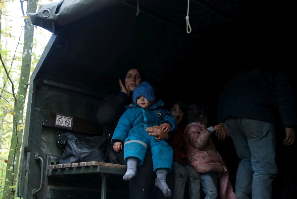 أسرة عراقية في مركبة عسكرية في هاجنوكا، بولندا، بعد عبورهم للحد من بيلاروسيا في الـ14 من تشرين أول / أكتوبر 2021 (الصورة من وكالة أنباء رويترز).