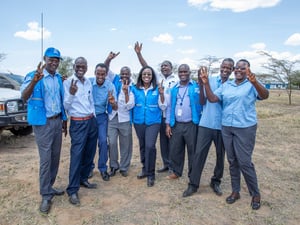 People in blue and grey uniform waving at the camera for a photo