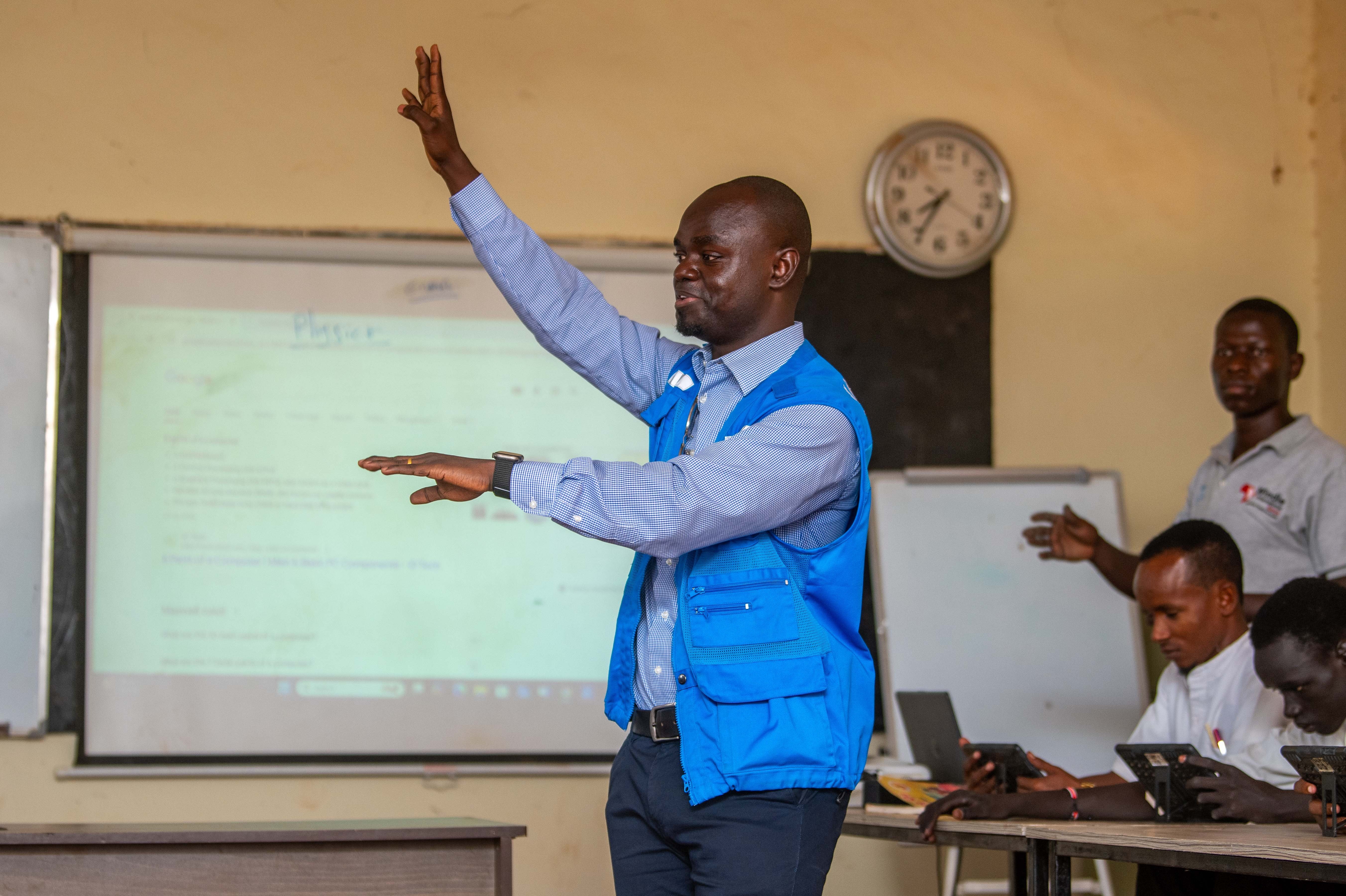 UNHCR Staff in a blue vest teaching a class