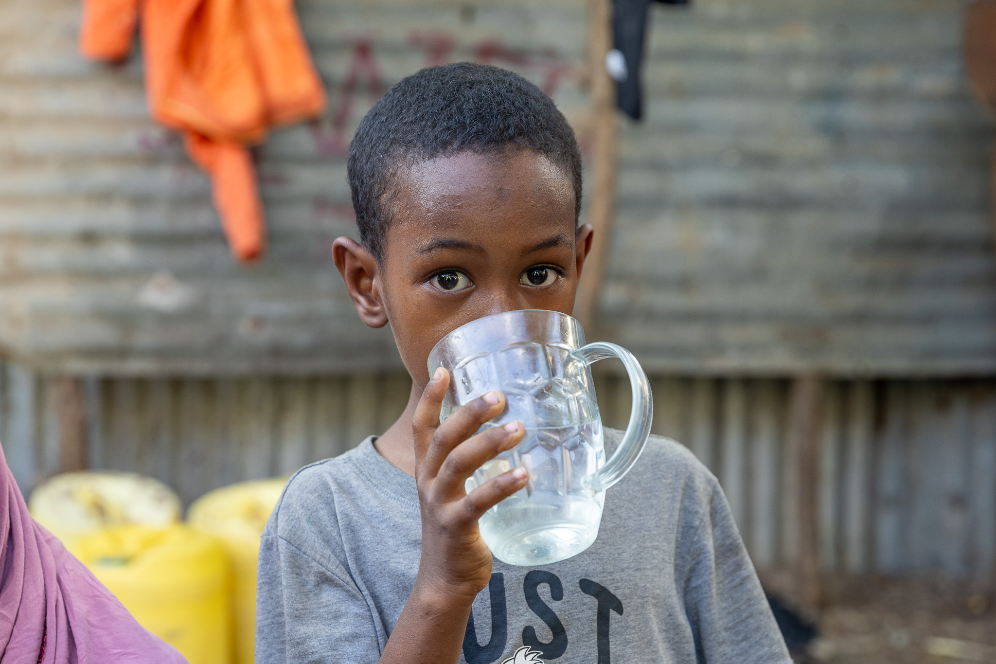 Eight-year-old Abdirazak drinks a glass of clean water in Kakuma, where reliable access to safe water helps families stay healthy.