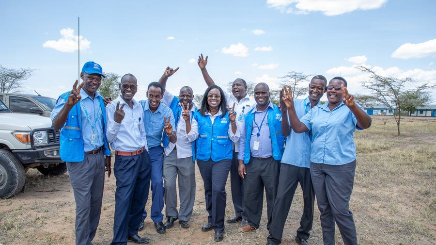 People in blue and grey uniform waving at the camera for a photo