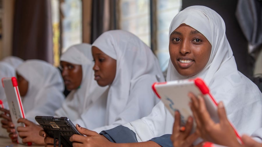 Girls in a white hijab sitting in a classroom holding tablets