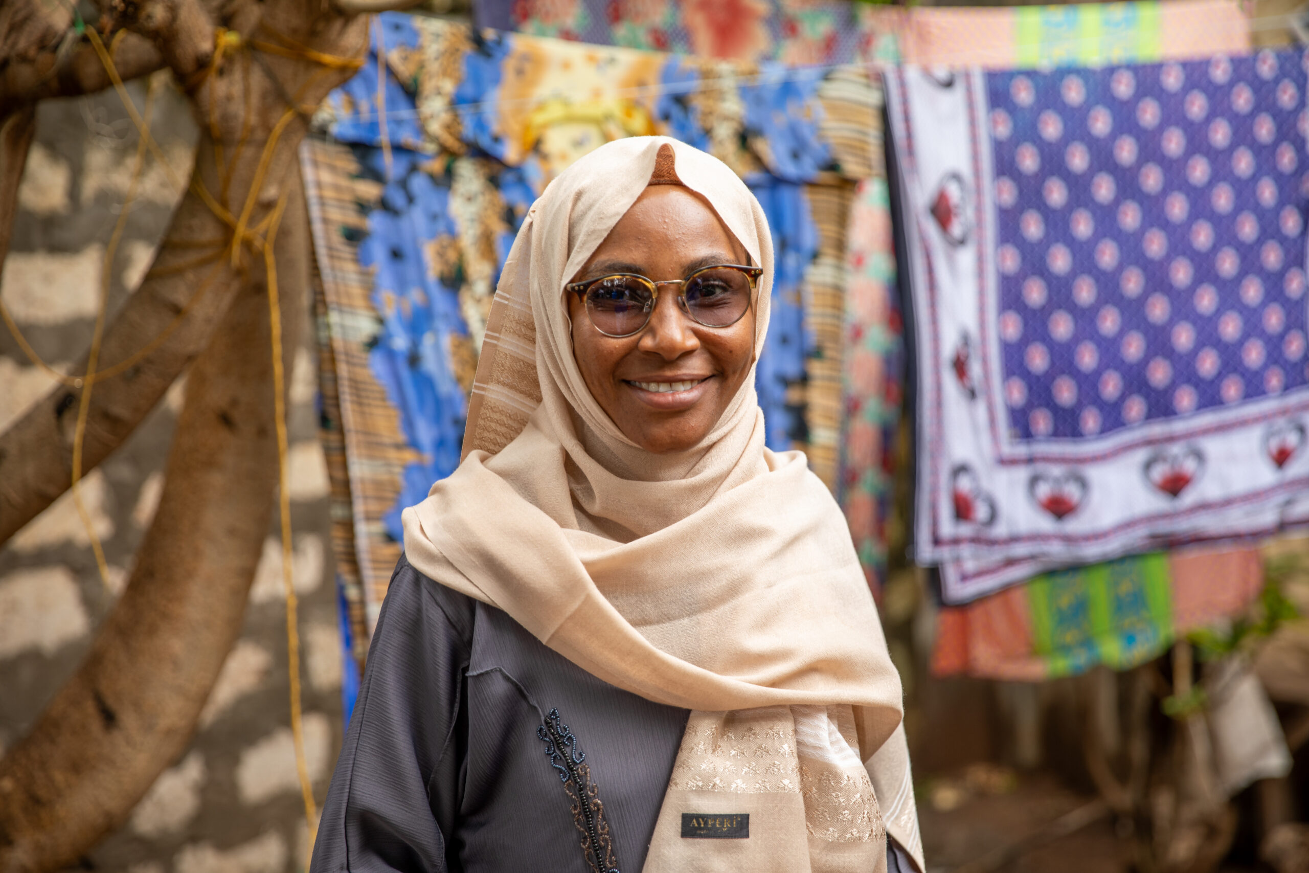 Portrait of a woman wearing glasses and a headscarf.