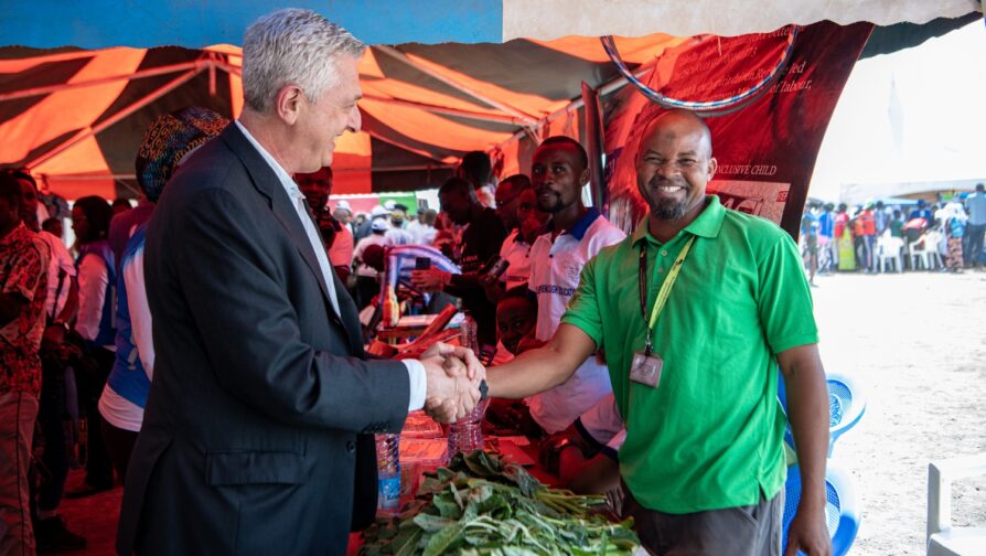 Two men shake hands at a vegetable stall.