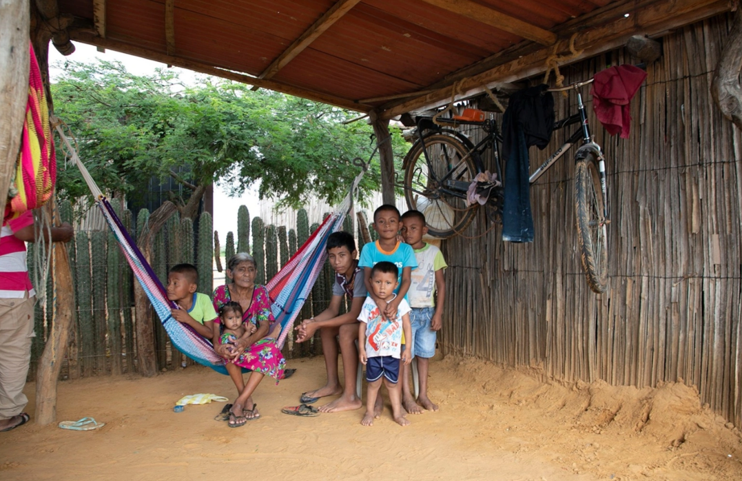 Venezuelan Wayuu family in the informal settlement of El Aeropuerto, in Uribia, next to their house built with yotojoro and bareque, traditional materials of this indigenous community.