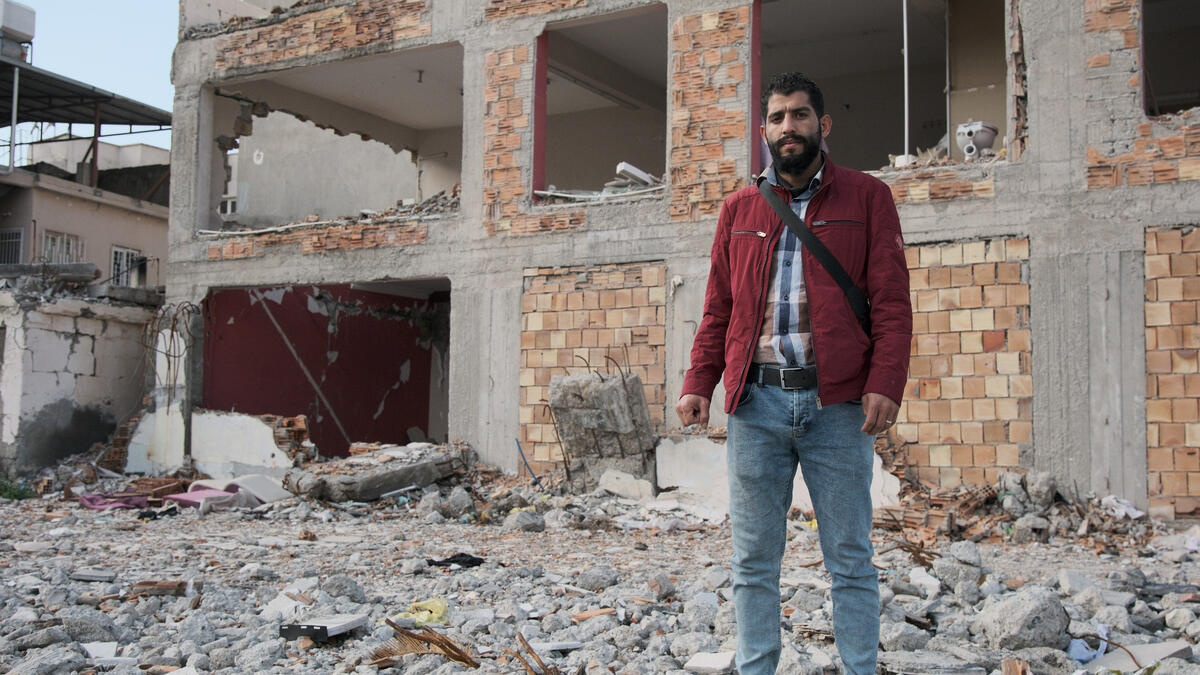 Turkiye. Syrian earthquake survivor Hassan Al-Assaf in front of rubbles.