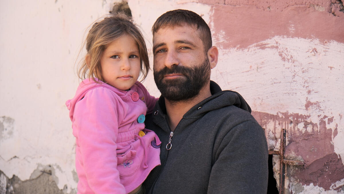Turkiye. Syrian earthquake survivor Tawfiq Bassam with his daughter, in front of a damaged building.
