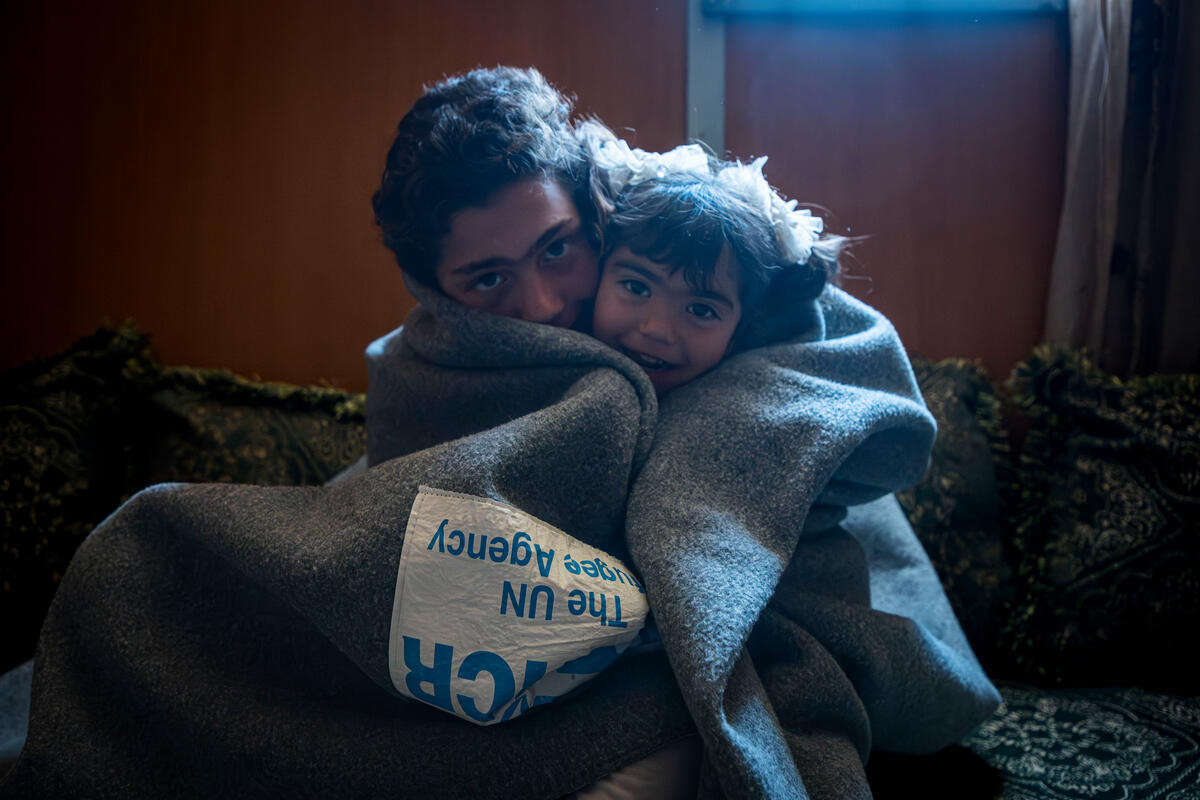 Jordan. Omran, 12 years old Syrian refugee, warming himself and his 3 years old sister Miral using UNHCR blanket inside their shelter in Zaatari refugee camp.
