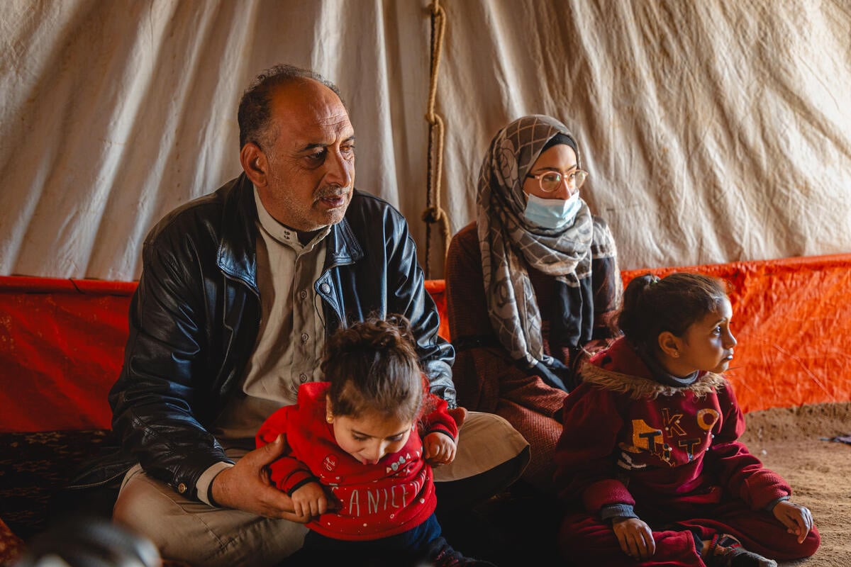 Jordan. Khaled sitting with his children inside their substandard shelter in Amman suburb