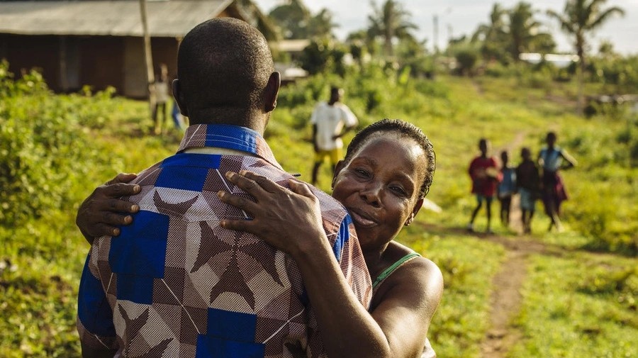 A former refugee from Côte d'Ivoire is embraced by his aunt upon returning home.