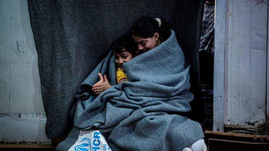 Jordan. Sundus, 11, cuddling her 6 years old brother Hisham with UNHCR blanket inside their shelter in Zaatari refugee camp.