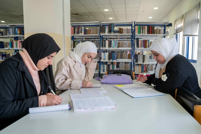 Sahar, 18 (right), Nada, 19 (center), and Basma, 18, study together in the library of Zarqa University in Jordan. Refugees from Syria currently residing in Zaatari camp, Sahar, Nada and Basma recently received DAFI scholarships to study English Translation at Zarqa University.