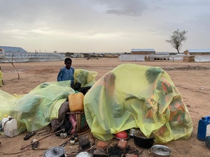 Refugees use plastic sheets to shelter from the rain at a spontaneous site for new arrivals from Sudan in Adre, eastern Chad.