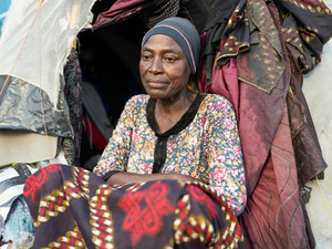 Une femme assise devant un abri de fortune.