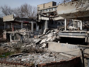 An exterior view of war-damaged buildings with collapsed roofs and walls.