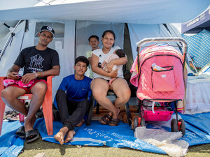 A family sits outside the entrance to a tent