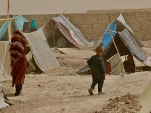 A woman and child walk between the makeshift tents in Nawabad Farabi-ha camp for internally displaced people in Mazar-e Sharif in northern Afghanistan.