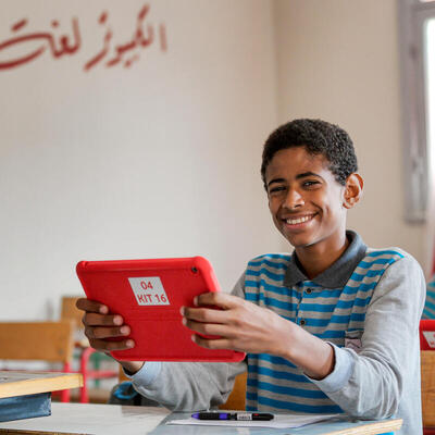 A boy holding a tablet smiles for the camera in Egypt. 