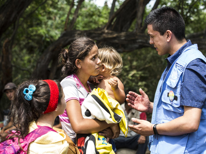 A woman with two young children speaks with a UNHCR staff member, in Colombia.