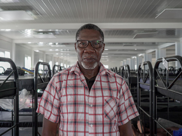 Buduka, an asylum-seeker from Nigeria, is pictured inside a bunk-bed-lined dormitory.