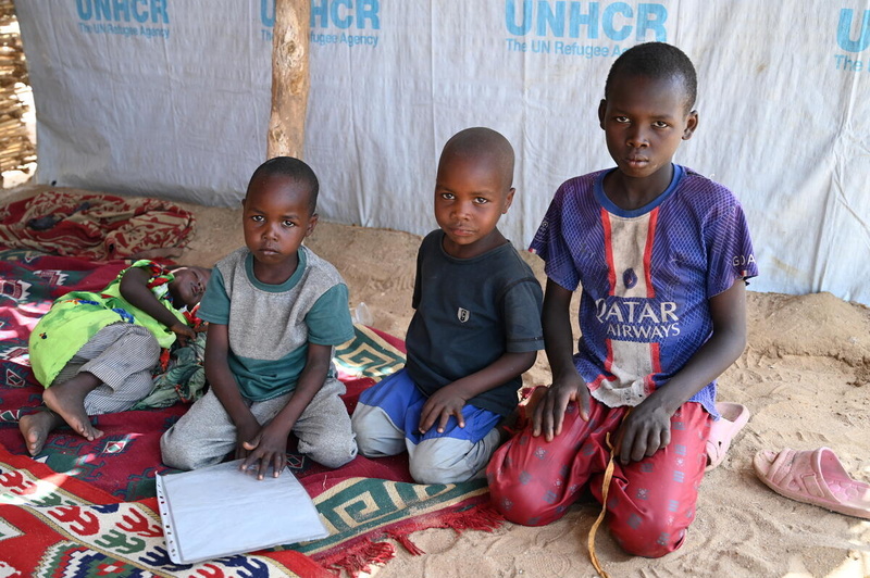 Maimouna, 3 ans, réfugiée soudanaise, fait la sieste tandis que son frère Saleh, 5 ans, et leurs frères d'accueil Salim et Zakaria sont agenouillés à côté d'elle. 