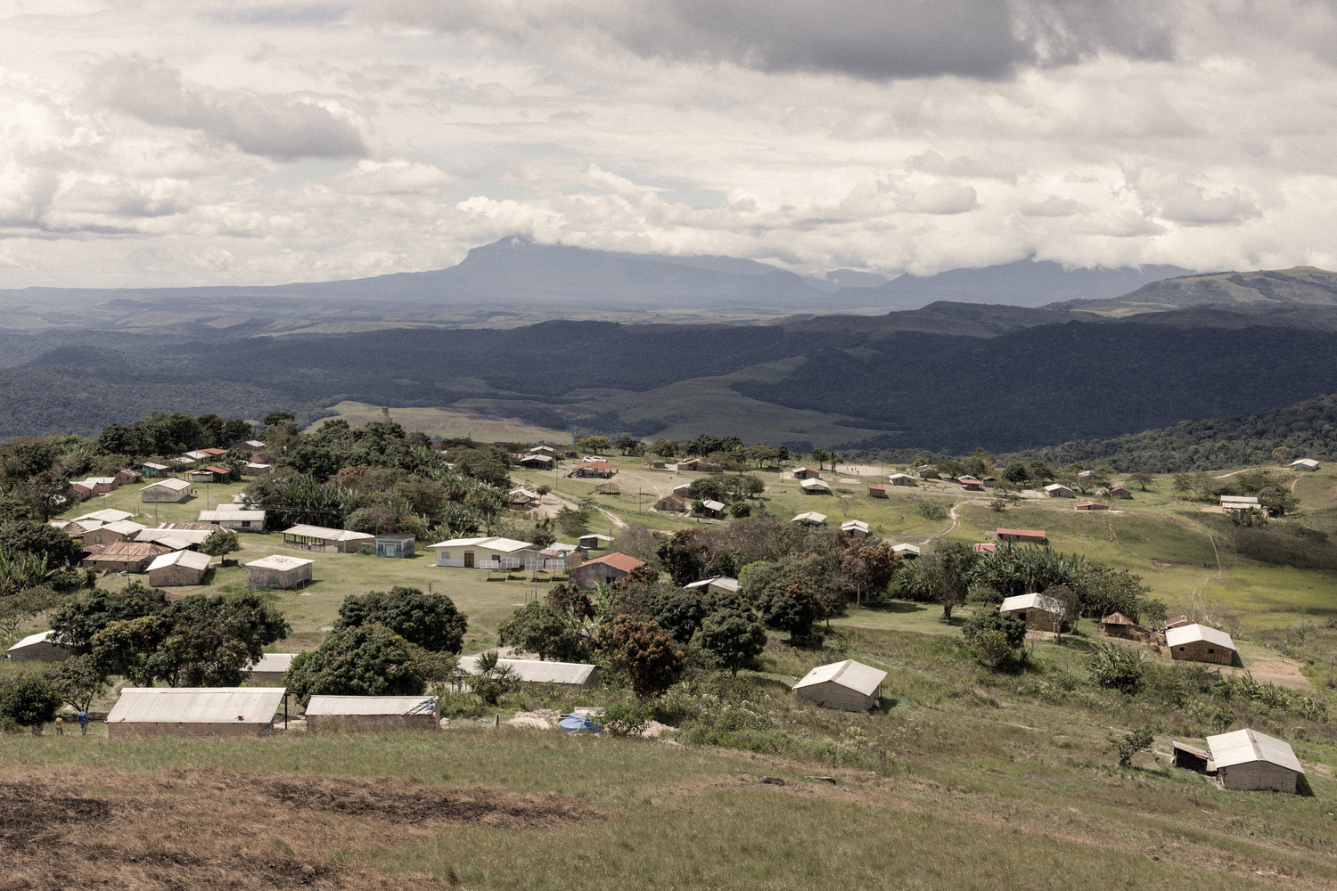 View of a village with green hills and mountains in the background