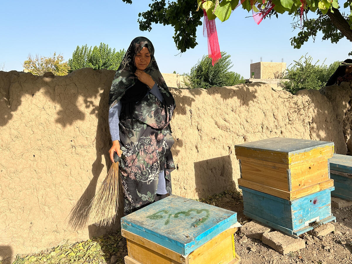 Une femme tient un balai qu'elle utilise pour débarrasser ses abeilles des insectes nuisibles.