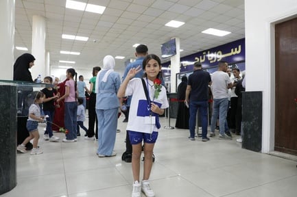 Haifa, 9 years old, gives the peace sign while holding a flower