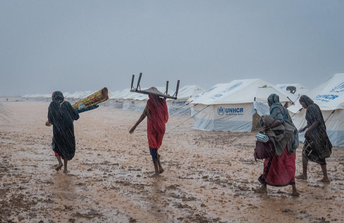 نازحات يحملن أمتعتهن عبر موقع مؤقت للتجمع غمرته المياه بالقرب من كسلا، السودان.