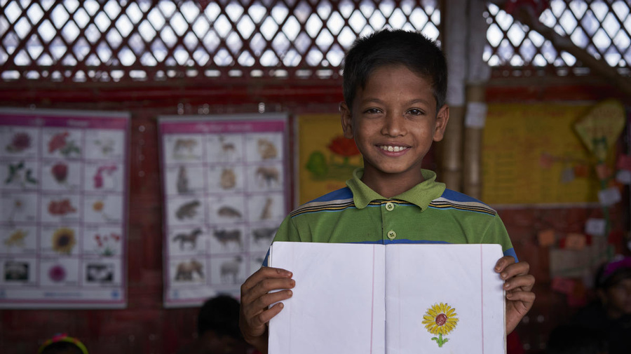Mohammad tient le dessin d'une fleur jaune qu'il a dessinée dans un centre d'apprentissage du camp de réfugiés rohingyas de Kutupalong, au Bangladesh.