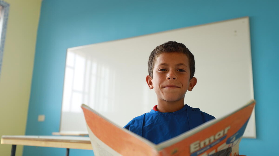 A young boy reading from a book. 